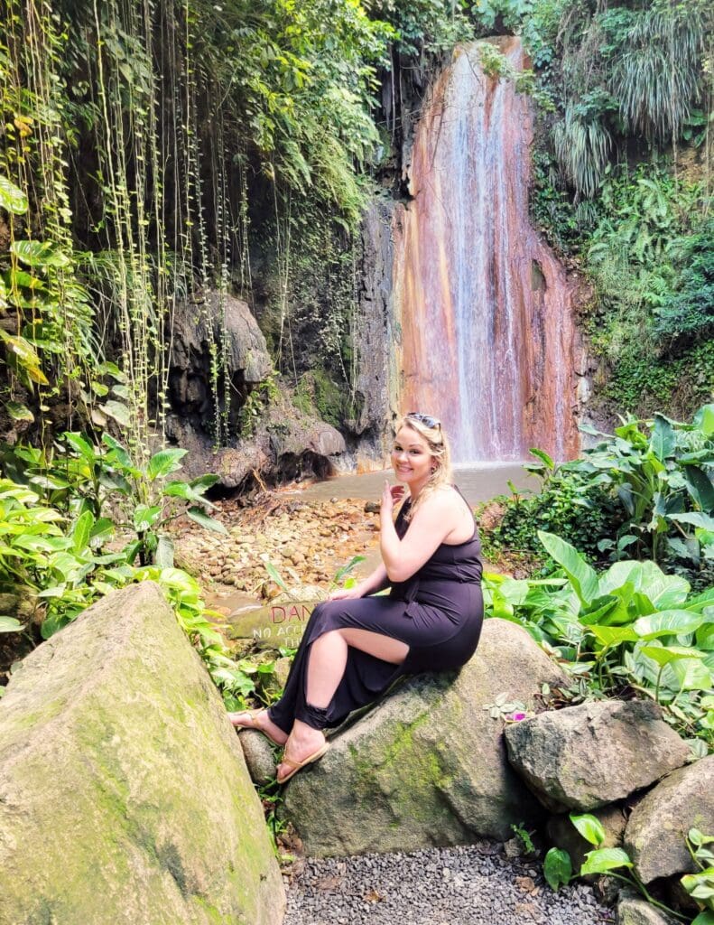 photo of woman sitting in front of Diamond Falls in St. Lucia