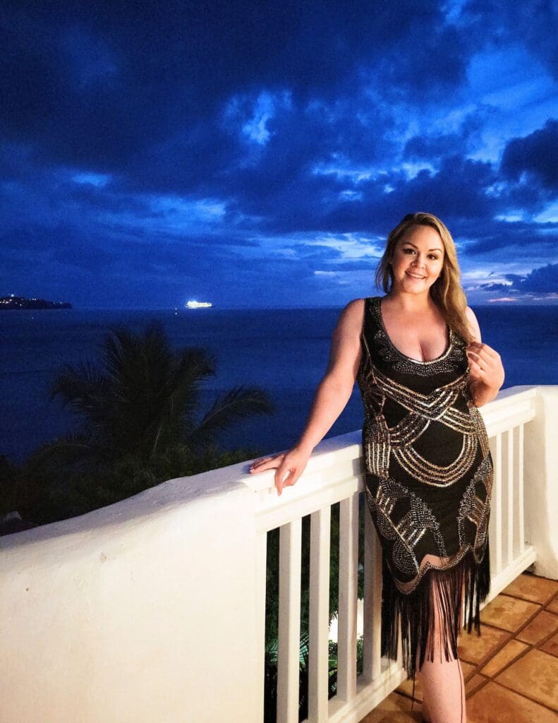 photo of woman standing on balcony smiling with bright blue sky behind her in St Lucia