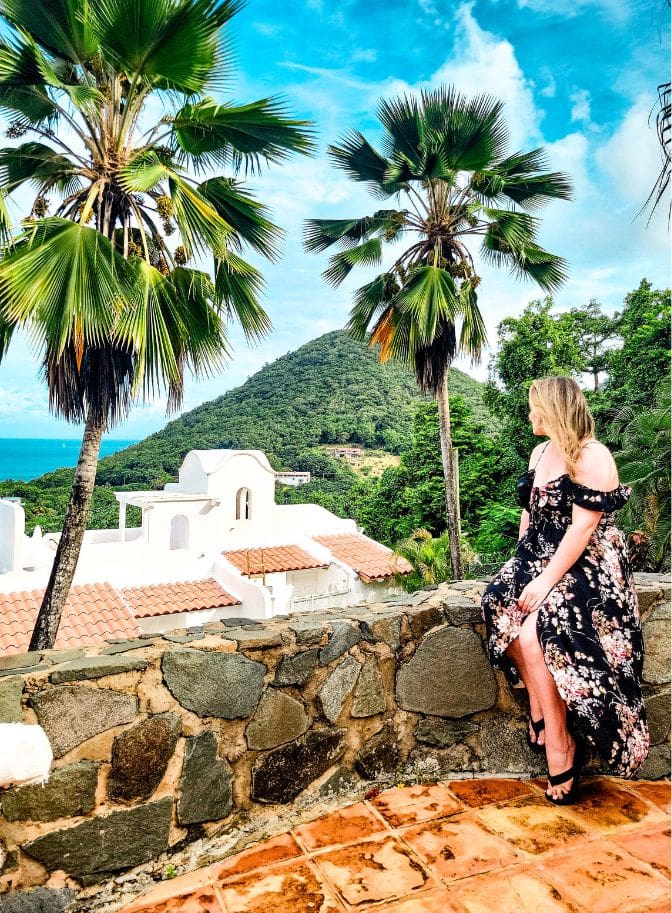 photo of woman sitting in a dress along a ledge and looking out at the view in St Lucia