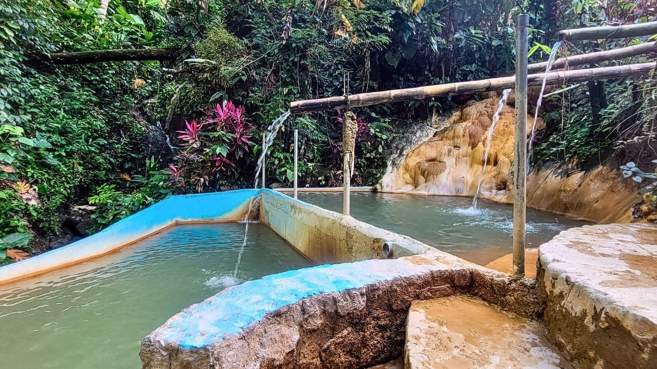 photo of mineral water flowing through bamboo into pools of water