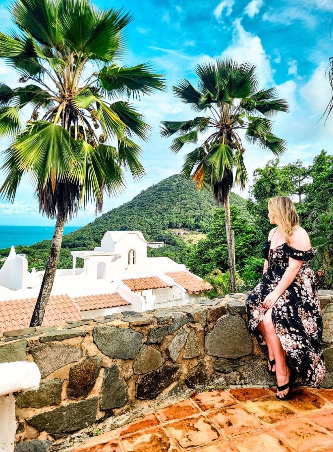 photo of woman sitting on rock ledge overlooking resort in St. Lucia