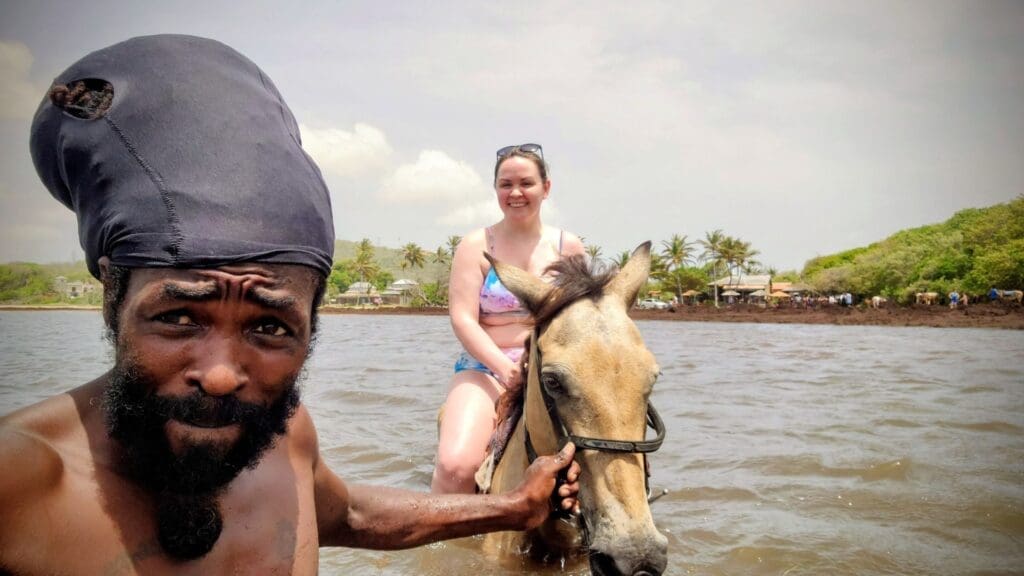 photo of woman horseback riding in the ocean with a man holding reins
