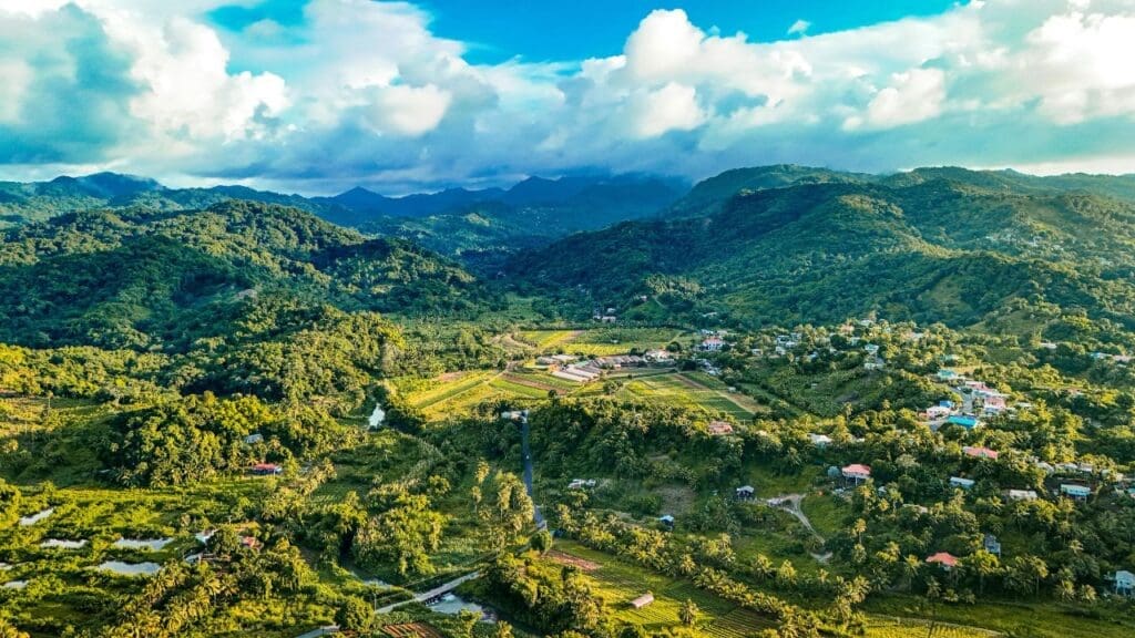 Aerial shot of St. Lucia over lush mountains and valleys under a vibrant blue sky