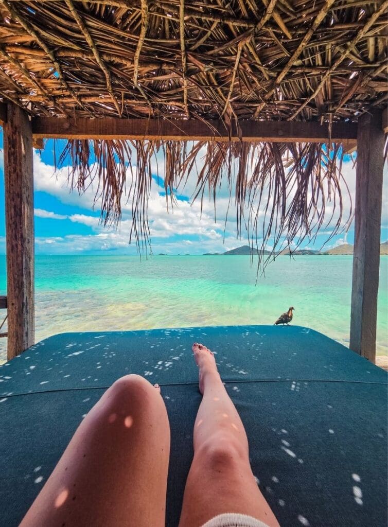 photo of woman's legs relaxing on cabana with a pigeon beside her