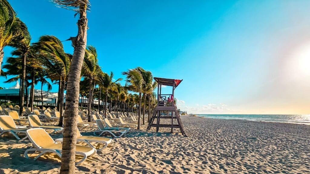photo of lifeguard station, palm trees, and lounge chairs at the beach in Mexico