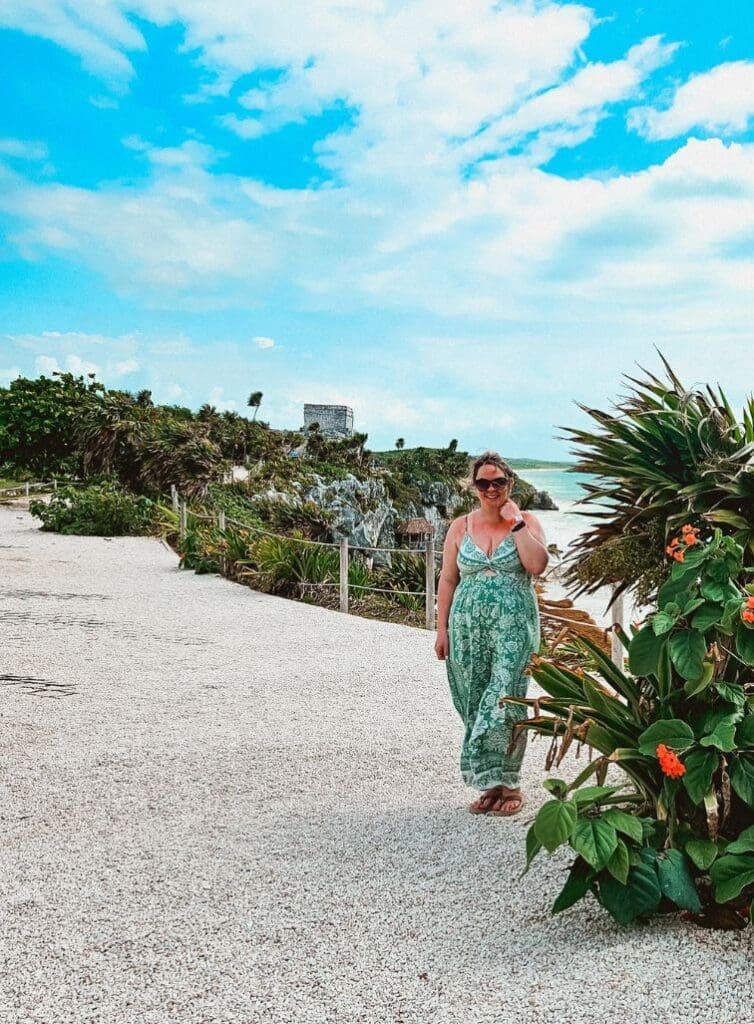 photo of woman standing in front of Caribbean Sea at Tulum Ruins