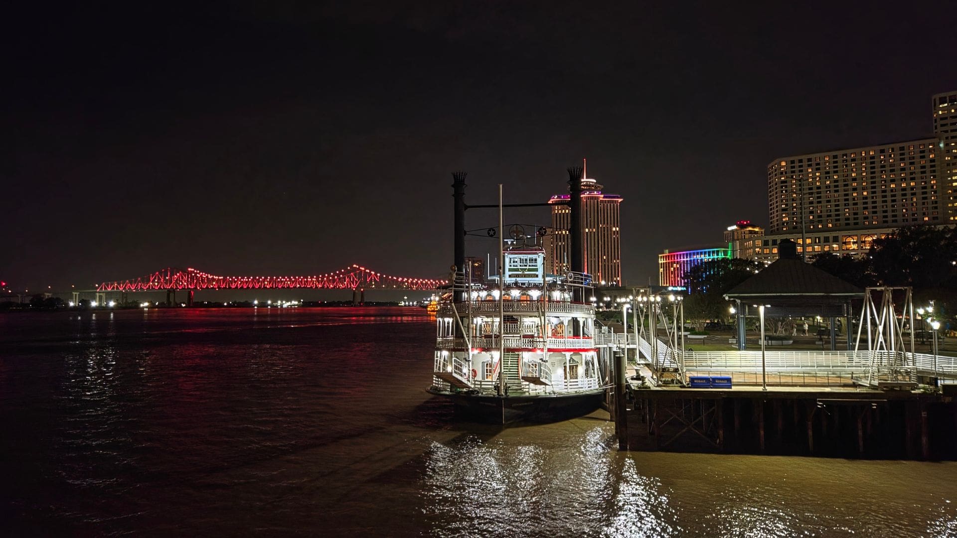 photo of New Orleans Steamboat at night with bridge lit up