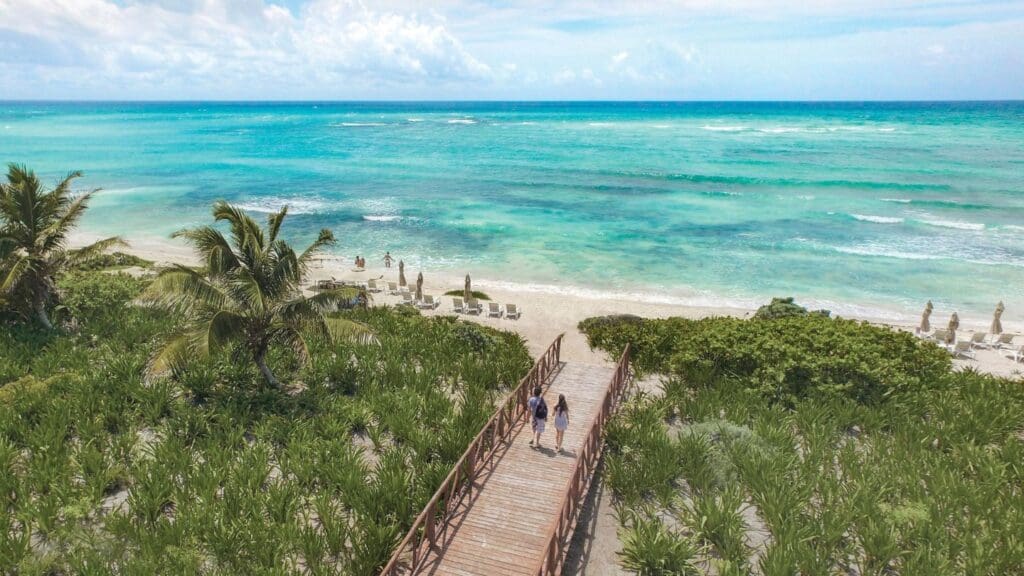 photo of couple walking down boardwalk towards beach at Riviera Maya