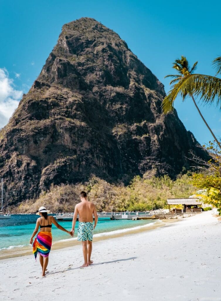 photo of couple walking along the beach beside the Pitons in St. Lucia